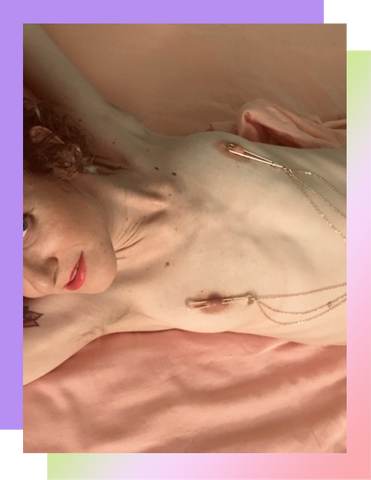 Photo of author laying down, wearing nipple clamps.